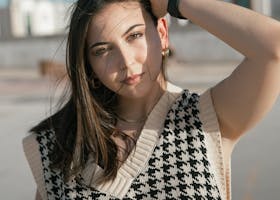 Portrait of a young woman in a stylish houndstooth sweater, enjoying a sunny day outdoors.